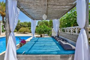 una cama bajo una pérgola junto a una piscina en Villas Guzman - Pura Vida, en Moraira