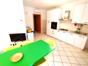 une cuisine avec une table verte et des placards blancs dans l'établissement Case vacanza Erica Igea Marina, à Bellaria-Igea Marina