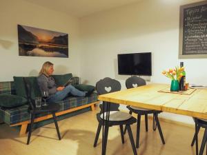 a woman sitting on a couch in a living room at Wohnung Weitsicht in Ruhpolding