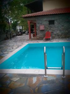 a blue swimming pool with a red chair next to a house at Guesthouse Kalypso in Kokkino Nero