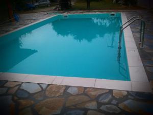 a large swimming pool with a metal rail in a yard at Guesthouse Kalypso in Kokkino Nero