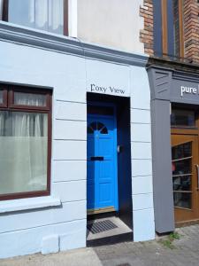 een blauwe deur aan de zijkant van een wit gebouw bij Foxy View in Dingle Town! in Dingle