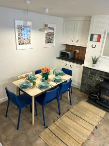 a dining room table with blue chairs and a kitchen at Foxy View in Dingle Town! in Dingle
