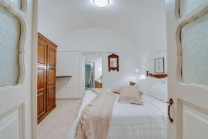 ein weißes Schlafzimmer mit einem Bett und einem Spiegel in der Unterkunft Moon Cactus Traditional Cave Suite with Jacuzzi in Mesariá