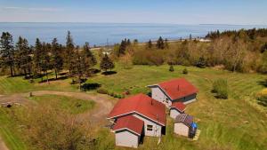 a house with a red roof on a green field at Stargazers Cove Cottages Otter in Middleton