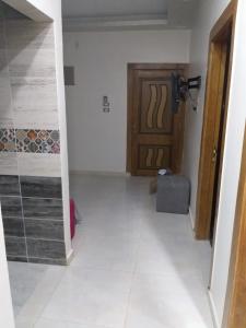 un couloir avec une porte et une chambre revêtue de carrelage blanc dans l'établissement Aswan Hotel Appartments, à Assouan