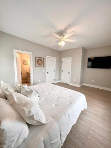 a bedroom with a large white bed and a flat screen tv at Swanky Seahorse in Carolina Beach +56 photos