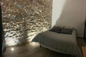 Jolie appartement en plein centre du village في ليه آرك-سور-ارجان: سرير في غرفة بجدار حجري