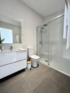 La salle de bains blanche est pourvue d'une douche et de toilettes. dans l'établissement Casas da Praia, à Furadouro