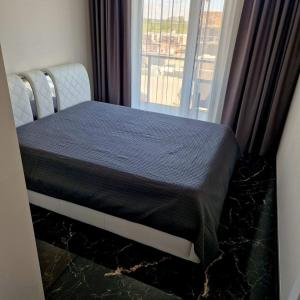 Bett in einem Zimmer mit Fenster in der Unterkunft Deluxe apartments - self check in in Klaipėda