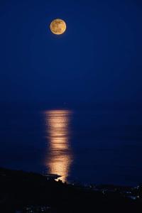 une pleine lune se levant au-dessus de l'eau la nuit dans l'établissement B&B La Scapola, à Mattinata