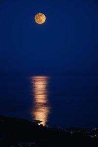 a full moon rising over the water at night at B&B La Scapola in Mattinata