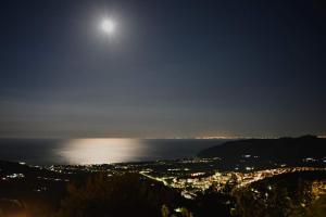 a view of a city at night with the moon at B&B La Scapola in Mattinata