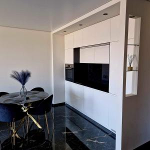 a dining room with a table and a kitchen at Deluxe apartments - self check in in Klaipėda