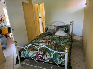 een kleine slaapkamer met een bed met een groene sprei bij Paradis le Clodyo in Sainte-Rose