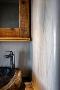 La salle de bains est pourvue d'un lavabo en pierre et d'un miroir. dans l'établissement mikro.kastro kalotaritissa in Chora Amorgos, à Amorgós