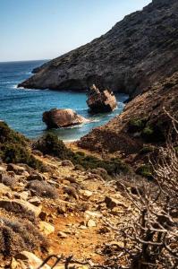 a rocky beach with a boat in the water at mikro.kastro kalotaritissa in Chora Amorgos in Amorgos