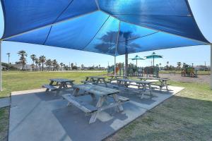 un groupe de tables de pique-nique sous un parapluie bleu dans l'établissement Vacation's Callin' on Ports O Call, à Île Padre