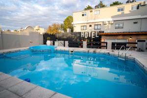 a swimming pool with blue water in front of a hotel at Nuevo Centro Hotel Villa Carlos Paz in Villa Carlos Paz