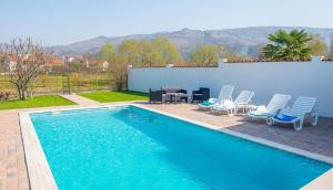 a swimming pool with chairs and a table next to a house at Villa Celleste in Mostar