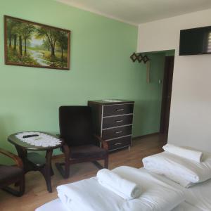 Cette chambre comprend deux lits, une chaise et un bureau. dans l'établissement Cztery Pory Roku, à Białowieża