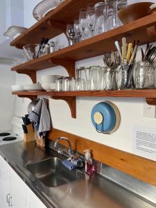 a kitchen counter with a sink and shelves with glasses at Wee Blue BnB- Central Cosy Villa in Timaru