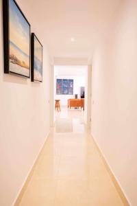 einen Flur mit weißen Wänden und Gemälden an den Wänden in der Unterkunft Luxury Apartments Sabi Waikiki con garaje in Corralejo