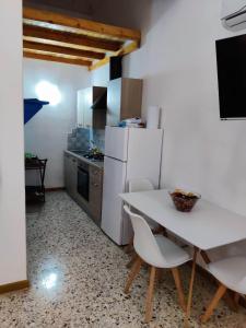 a kitchen with a white table and a white refrigerator at Il Giardino su Lido Burrone in Favignana