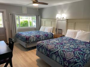 a bedroom with two beds and a table and a window at Kennebunkport Motor Lodge in Kennebunkport +58 photos