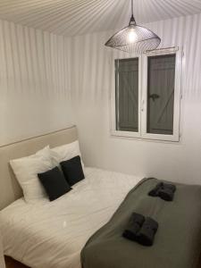 1 cama blanca con 2 almohadas negras y ventana en OSoleMio Moliets, en Moliets-et-Maa