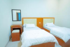 mały pokój z 2 łóżkami i lustrem w obiekcie Kartika Syariah Guest House w mieście Surakarta