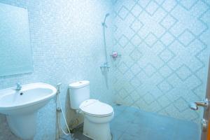 a bathroom with a toilet and a sink and a shower at Kartika Syariah Guest House in Solo