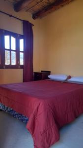 Un dormitorio con una cama con una manta roja. en El Convento de Tilcara en Tilcara