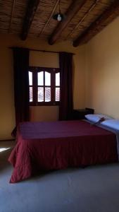 a bedroom with a red bed with a window at El Convento de Tilcara in Tilcara