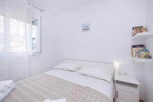 a white bedroom with a bed and a window at Feel like Home in Podstrana