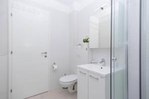 a white bathroom with a toilet and a glass shower at Feel like Home in Podstrana