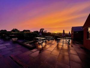 a group of picnic tables with a sunset in the background at Shepherds Gate at The Royal Oak Much Marcle in Preston