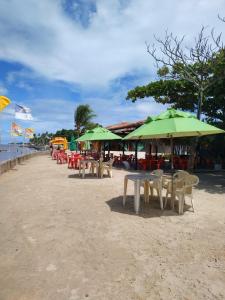 um grupo de mesas e guarda-sóis numa praia em Casa sol e mar pe na areia em Paulista