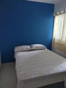 a bedroom with a blue wall and a bed at Casa sol e mar in Paulista