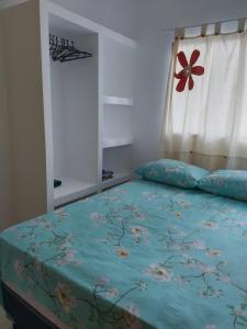 1 dormitorio con 1 cama con edredón azul y ventana en Casa sol e mar pe na areia, en Paulista