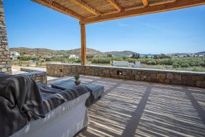 a patio with a couch and a stone wall at SeaeyeVillas 1 in Livadi