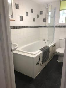 a white bathroom with a tub and a toilet at Seaton, Devon, two bed apartment, just off the sea front. in Seaton +16 photos
