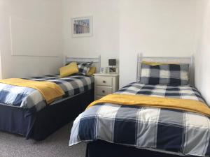 two beds sitting next to each other in a bedroom at Seaton, Devon, two bed apartment, just off the sea front. in Seaton