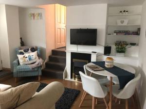 a living room with a television and a table and chairs at Seaton, Devon, two bed apartment, just off the sea front. in Seaton