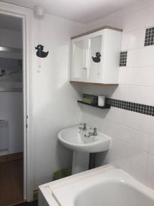 a white bathroom with a sink and a cabinet at Seaton, Devon, two bed apartment, just off the sea front. in Seaton
