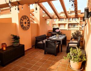 d'une terrasse avec une table, des chaises et une horloge. dans l'établissement Spacious and stylish penthouse in Mijas, à Mijas