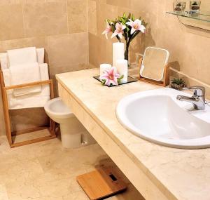 La salle de bains est pourvue d'un lavabo, de toilettes et de fleurs. dans l'établissement Spacious and stylish penthouse in Mijas, à Mijas