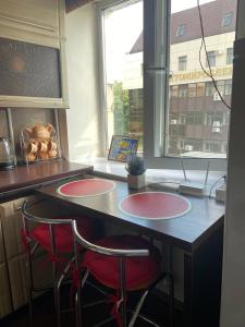 a kitchen with two red stools at a counter with a window at Apartment in Shoduar's park in Zhytomyr