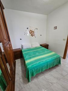 a bedroom with a bed with a green blanket on it at Tuppo delle pile Seaview in Peschici