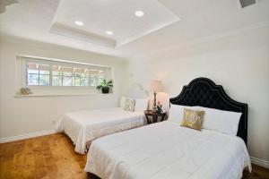 2 bedden in een slaapkamer met witte muren en een raam bij 5B3B Villa Near Disneyland, Beach，Golf Course in Santa Ana